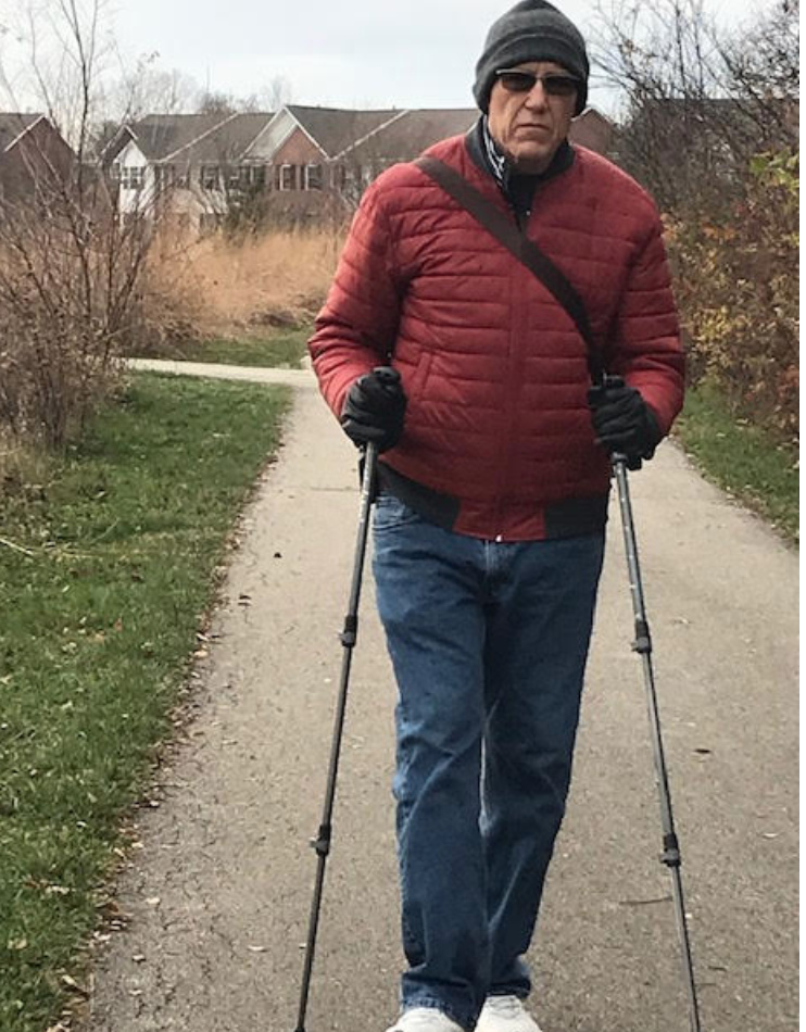 Rick walking on a path with 2 walking sticks